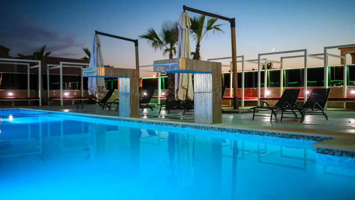 Pool von Boutique Apartments Blitz bei Sonnenuntergang, mit Palmen und dem Gebäude im Hintergrund